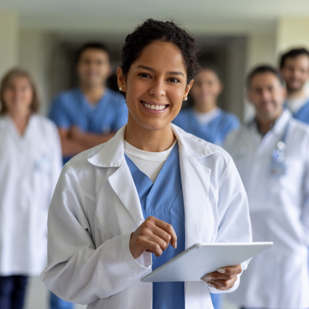 Happy female doctor leading a team of healthcare workers at the hospital and looking at the camera smiling